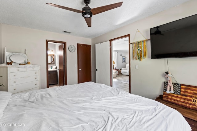 bedroom featuring ceiling fan, hardwood / wood-style floors, a textured ceiling, and ensuite bath