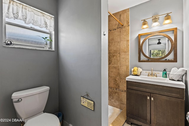 bathroom featuring vanity, tiled shower, and toilet