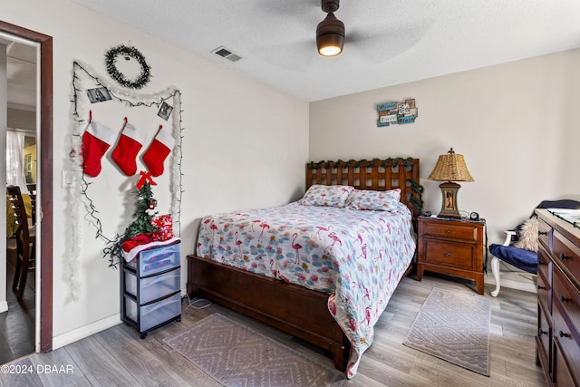 bedroom with ceiling fan, hardwood / wood-style floors, and a textured ceiling