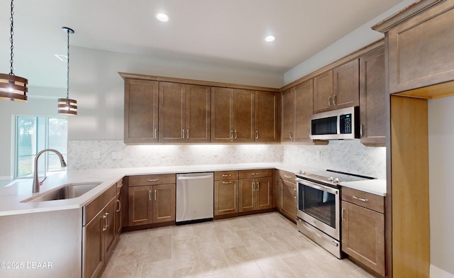 kitchen with pendant lighting, sink, decorative backsplash, and appliances with stainless steel finishes