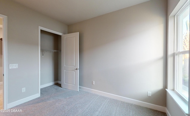 unfurnished bedroom with multiple windows, light colored carpet, and a closet