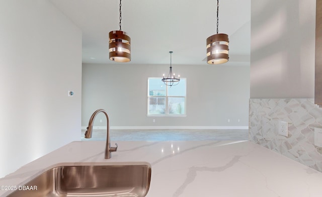 kitchen featuring hanging light fixtures, sink, and light stone counters