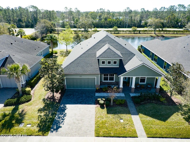 view of front of house featuring decorative driveway, covered porch, a front lawn, and a garage