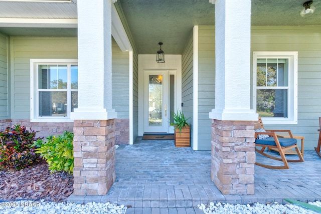 view of exterior entry featuring covered porch and stone siding