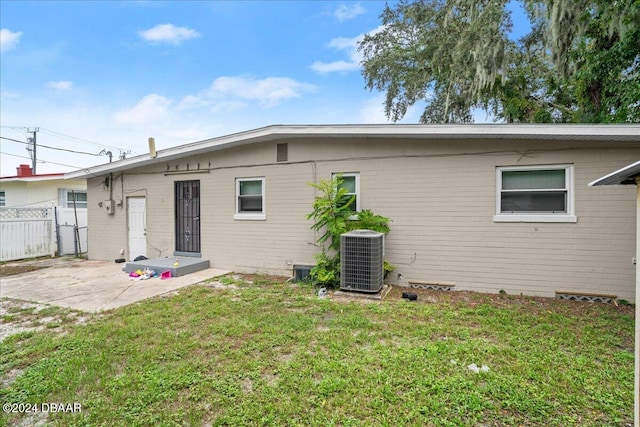 rear view of house featuring a lawn, cooling unit, and a patio area