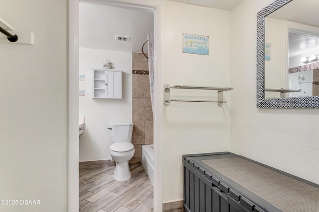 bathroom with toilet and tiled shower / bath