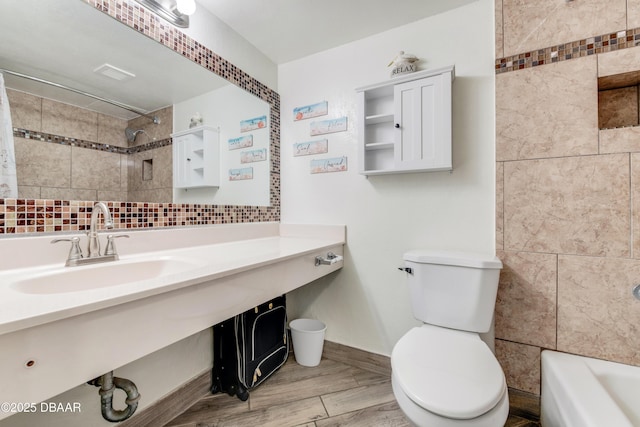 full bathroom with sink, tiled shower / bath, backsplash, and toilet