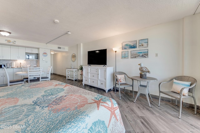 bedroom with a textured ceiling and light hardwood / wood-style floors