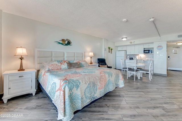 bedroom featuring white refrigerator and light hardwood / wood-style flooring