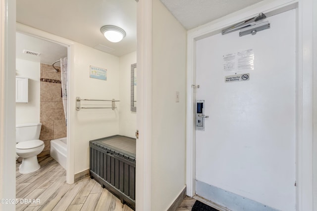 bathroom featuring tiled shower / bath, hardwood / wood-style floors, radiator heating unit, and toilet