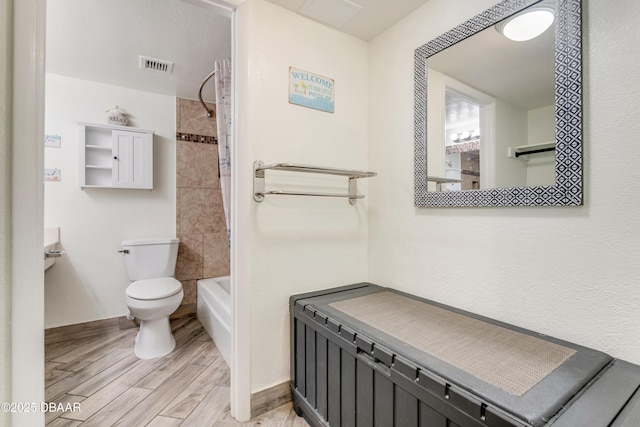 bathroom featuring toilet and tiled shower / bath combo