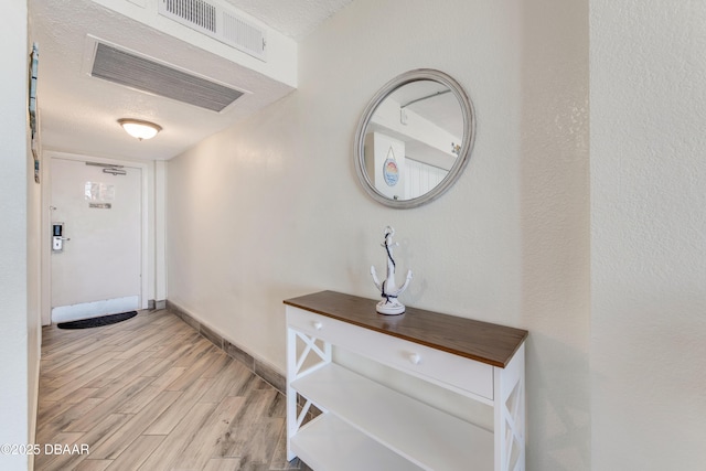 hallway featuring light hardwood / wood-style floors and a textured ceiling