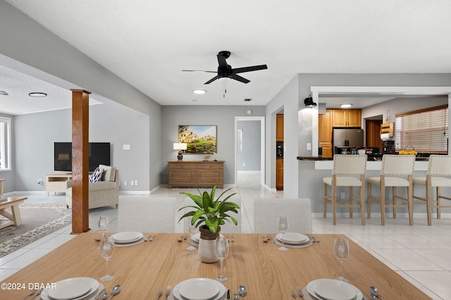 tiled dining room with ornate columns, a healthy amount of sunlight, and ceiling fan