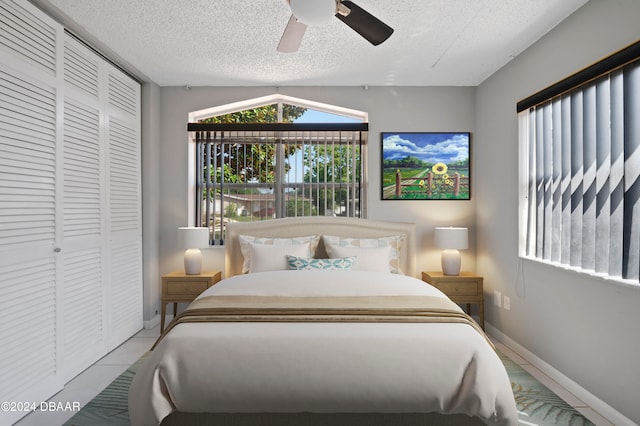 bedroom featuring light tile patterned floors, a textured ceiling, ceiling fan, and a closet