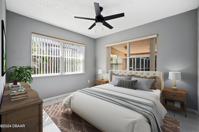 tiled bedroom with multiple windows, a textured ceiling, and ceiling fan