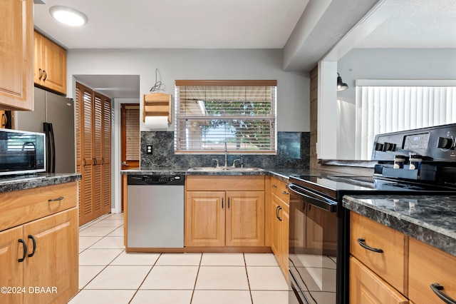 kitchen with backsplash, appliances with stainless steel finishes, light tile patterned floors, sink, and dark stone countertops