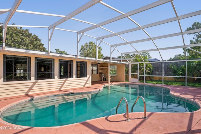 view of pool with glass enclosure and a patio area