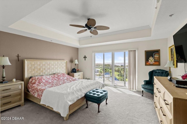 bedroom with ceiling fan, access to exterior, and a tray ceiling