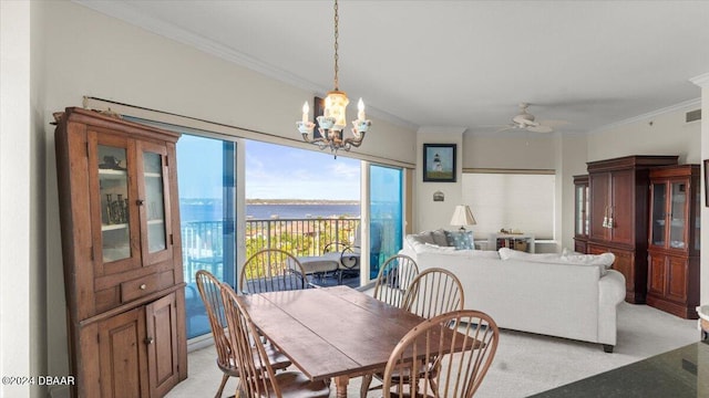 dining space with a water view, light colored carpet, crown molding, and ceiling fan with notable chandelier