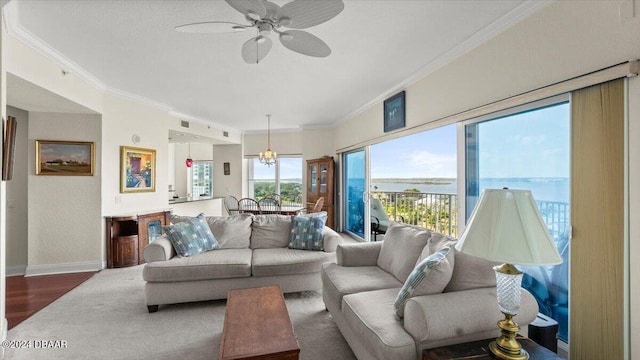 living room featuring dark hardwood / wood-style flooring, a water view, ornamental molding, and ceiling fan with notable chandelier