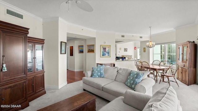 living room with ceiling fan with notable chandelier, light colored carpet, and crown molding