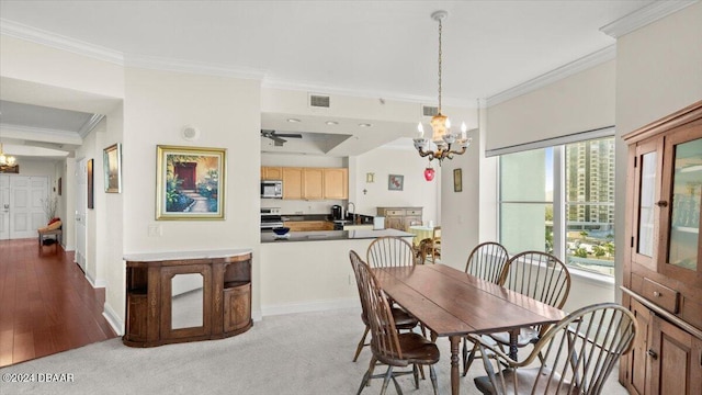 dining space featuring ornamental molding, light wood-type flooring, ceiling fan with notable chandelier, and sink