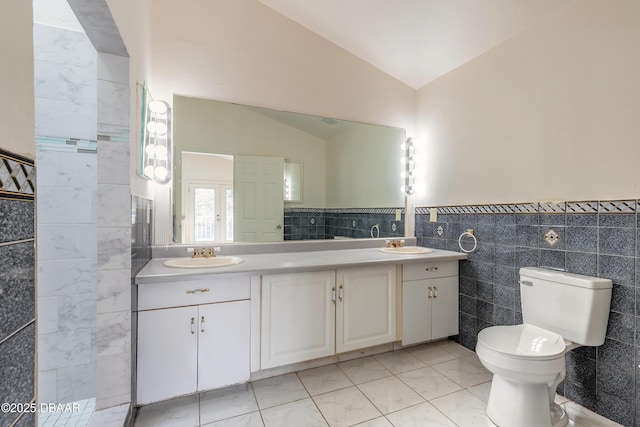 full bathroom with lofted ceiling, double vanity, a sink, and tile walls