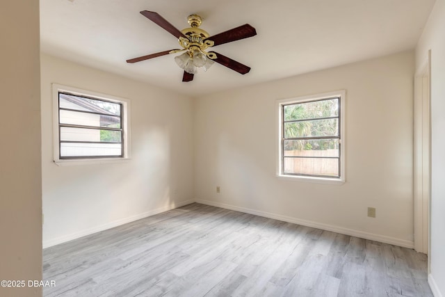 spare room with a ceiling fan, baseboards, a wealth of natural light, and wood finished floors