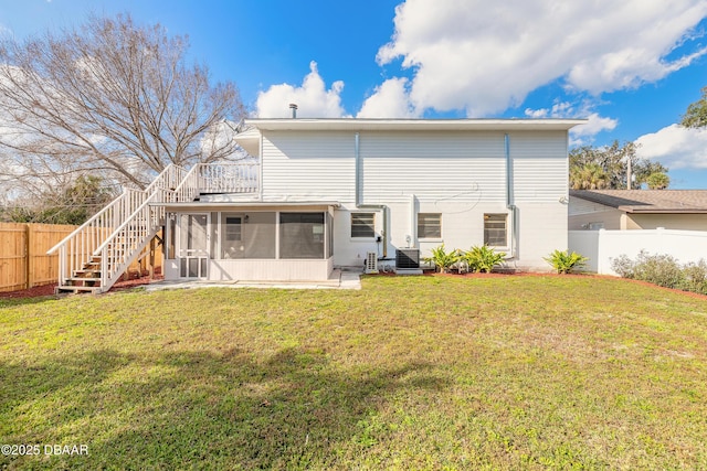 back of property with a sunroom, a fenced backyard, stairs, and a lawn