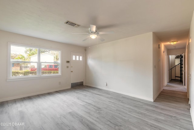 unfurnished room with light wood finished floors, visible vents, baseboards, a ceiling fan, and stairway