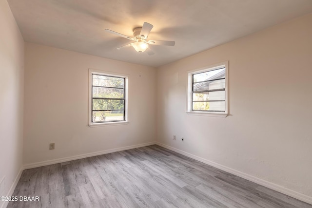 spare room featuring plenty of natural light, wood finished floors, and baseboards