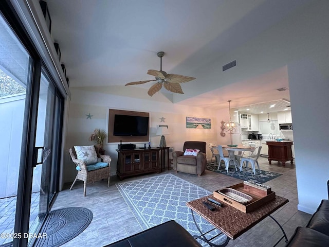 living room with hardwood / wood-style floors, ceiling fan with notable chandelier, and vaulted ceiling