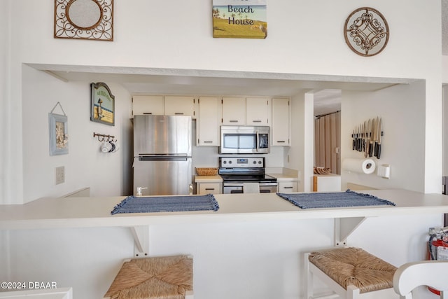 kitchen with a kitchen bar, kitchen peninsula, and appliances with stainless steel finishes