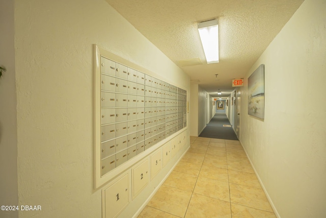 hall featuring a textured ceiling, mail boxes, and light tile patterned flooring