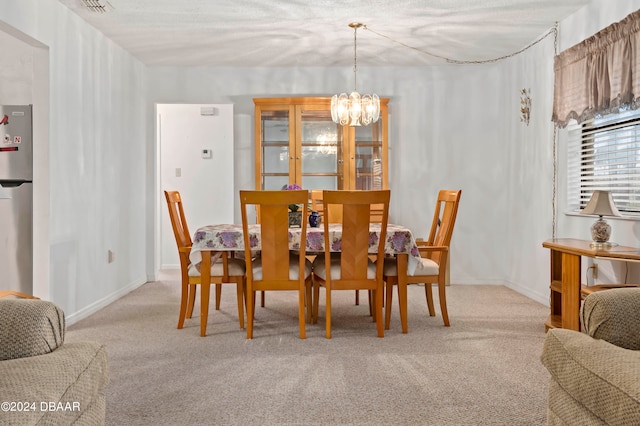 dining area featuring an inviting chandelier, light carpet, and a textured ceiling