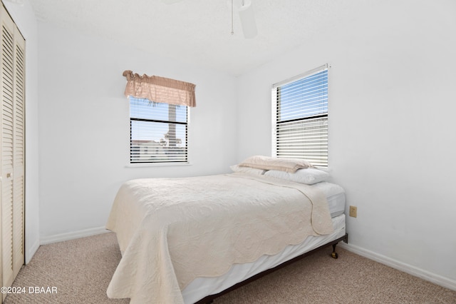 carpeted bedroom featuring ceiling fan and a closet