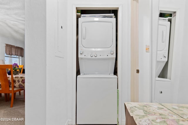 laundry area featuring stacked washer and clothes dryer and carpet floors