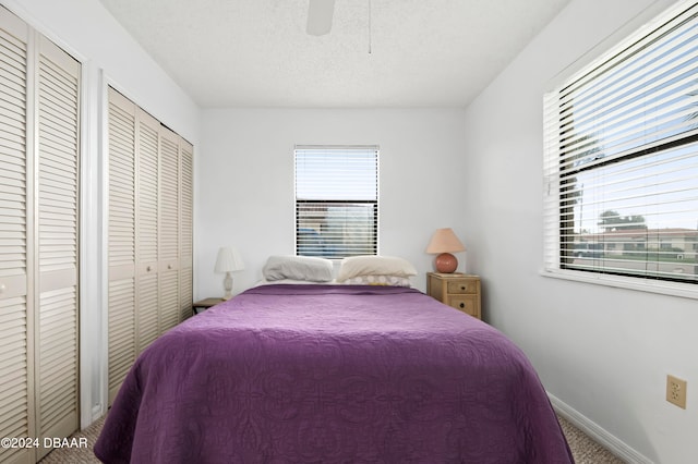 carpeted bedroom with ceiling fan, multiple windows, and a textured ceiling