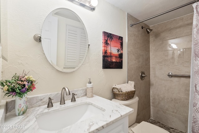 bathroom featuring tiled shower, vanity, and toilet