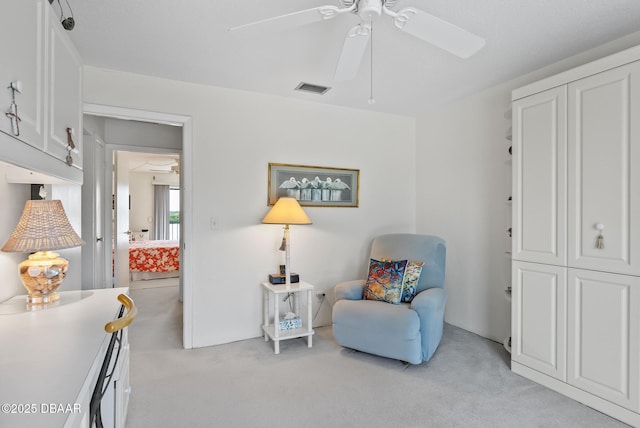 sitting room with ceiling fan and light colored carpet