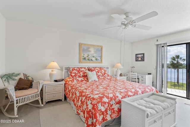 bedroom with multiple windows, a water view, access to exterior, and a textured ceiling