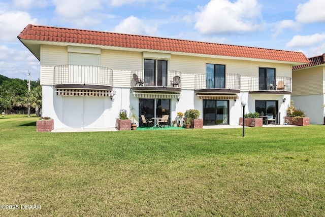 rear view of property featuring a yard and a balcony