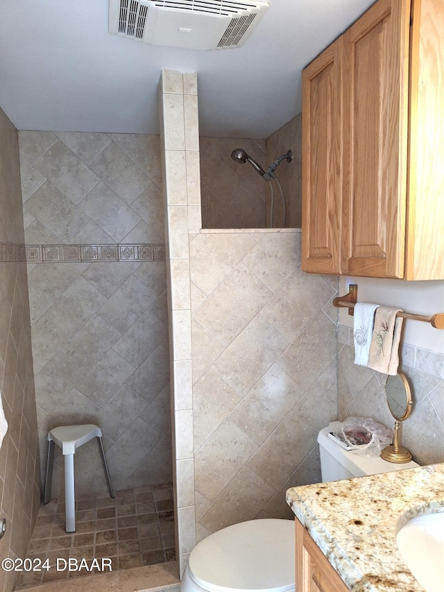 bathroom with toilet, vanity, tile walls, and tiled shower