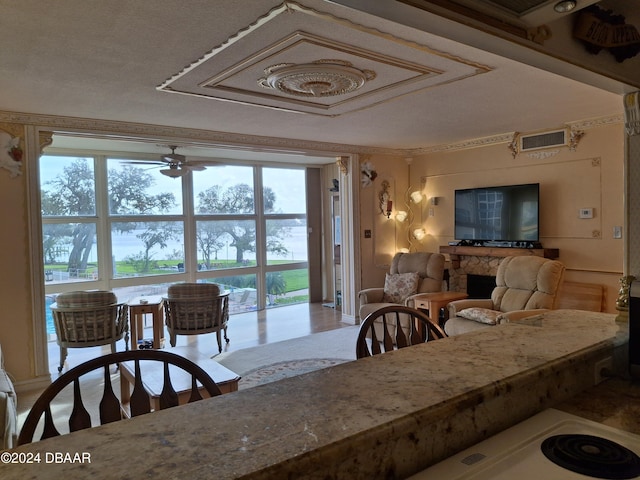 dining space with ceiling fan, a healthy amount of sunlight, and a fireplace