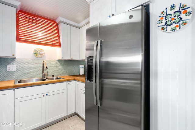 kitchen with white cabinets, stainless steel refrigerator with ice dispenser, butcher block counters, and sink