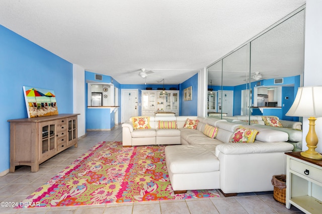 living room featuring a textured ceiling, light tile patterned floors, and ceiling fan