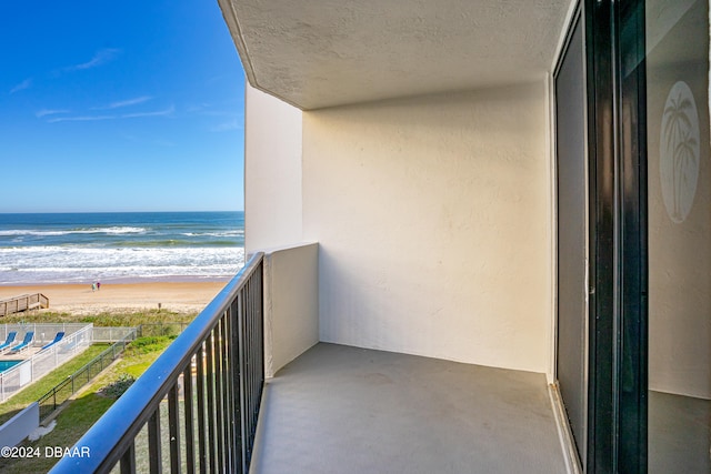 balcony featuring a beach view and a water view