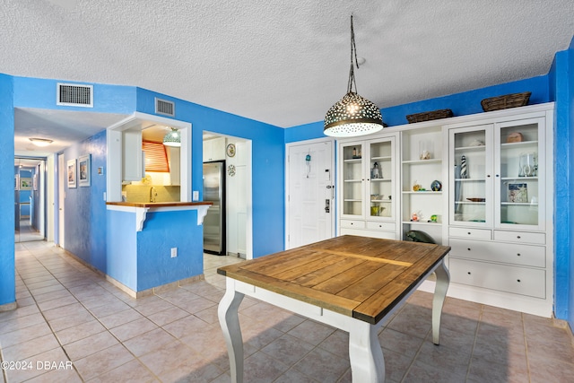 tiled dining area with a textured ceiling and sink