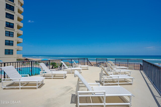 view of patio featuring a community pool, a water view, and a balcony