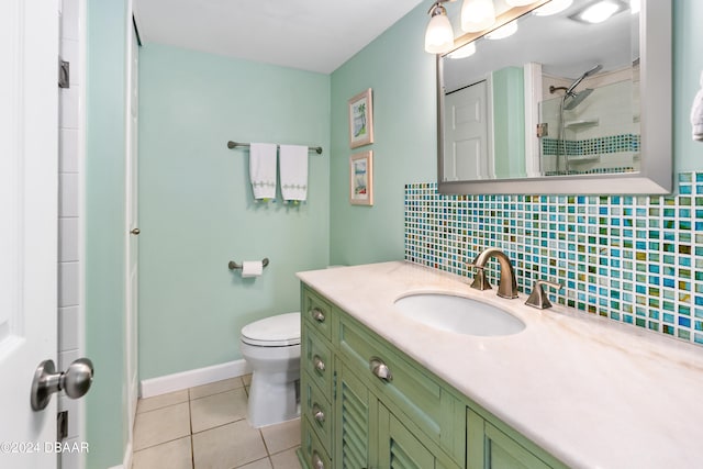 bathroom with tasteful backsplash, a tile shower, vanity, tile patterned floors, and toilet